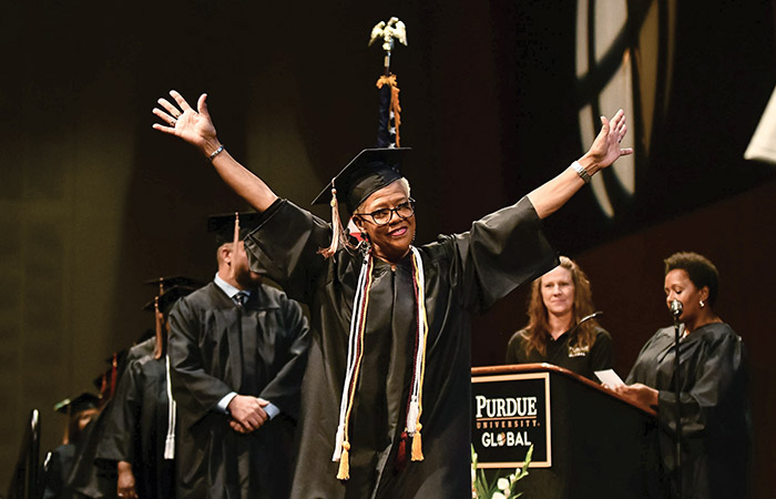 a purdue global graduate on the commencement stage