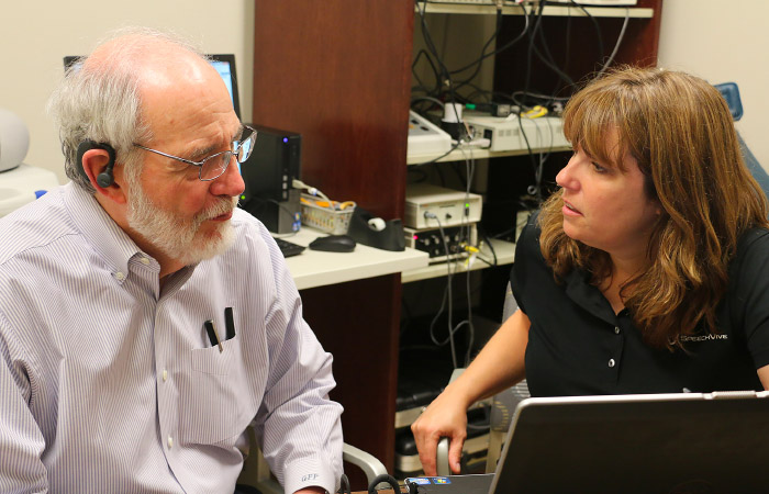 an elderly man taking a hearing test from a woman