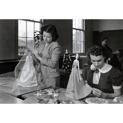 two girls making small scale mannequin clothes