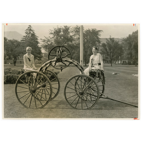 bells on wheels with two women sitting on either side of the bells