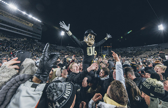 Purdue Pete is lifted up on the football field by celebrating fans