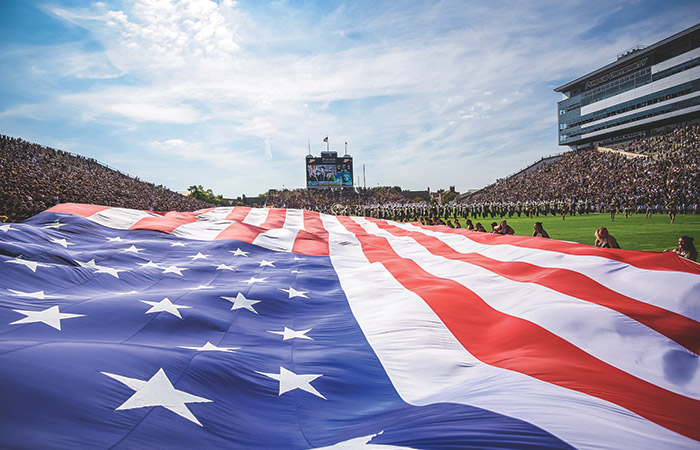 a huge american flag unfurled on the football field