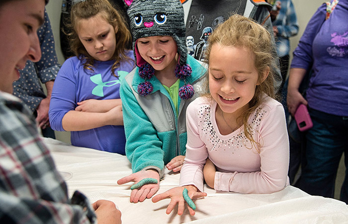 girls hold caterpillars at the bug bowl