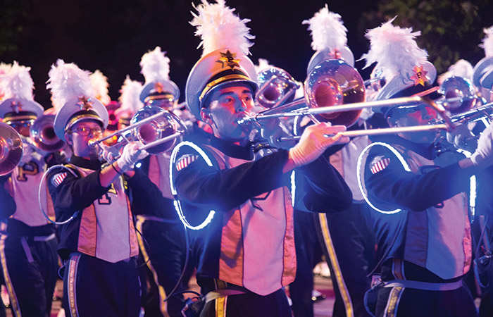 the marching band plays at nigth wearing outfits that are lit by led lights