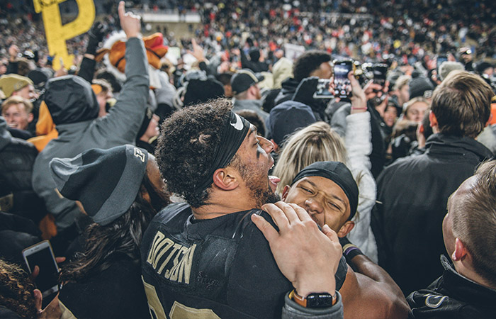 fans celebrate a football victory on the field with the players