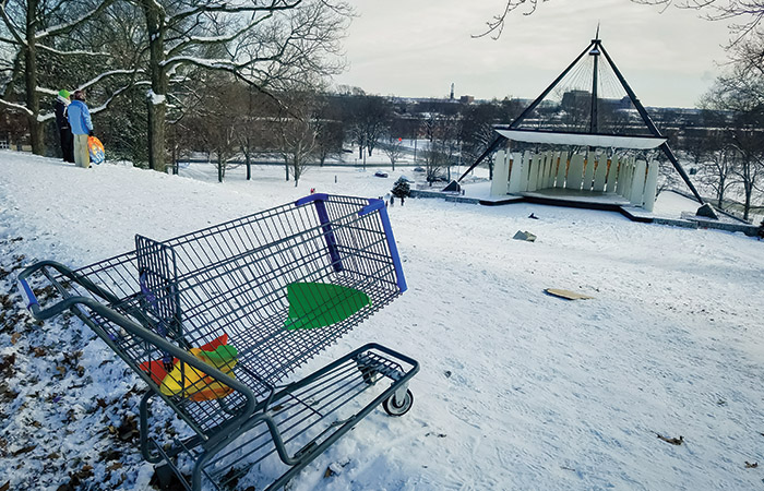 a shopping cart at the top of a snow-covered slayter hill