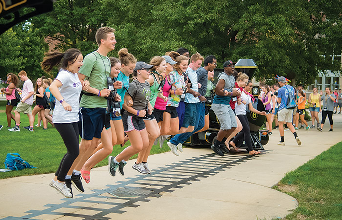 students jumping over some train tracks