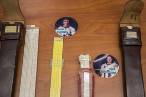 Slide rules next to photos of the astronauts who owned them