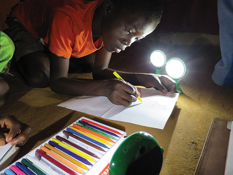 a girl colors a picture by light from a flashlight