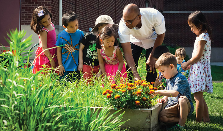 an adult and children looking at plants growing in the raised beds of Marriott Garden