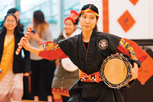 asian woman in traditional attire playing a drum